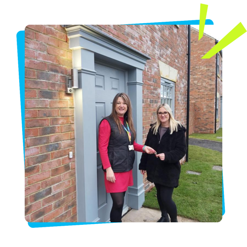 A North Star team member handing over a key to someone outside a brand new front door.